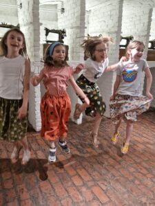 Joie des petites filles montrant leur jupe cousues à l'occasion d'un cours de couture parents-enfants